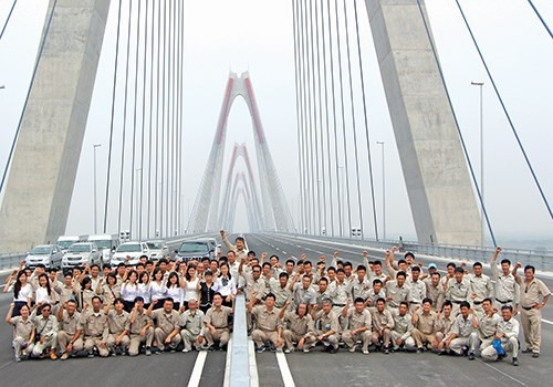 Niềm vui sướng lớn nhất có lẽ thuộc về những người thợ đã góp sức xây nên cây cầu (Trong ảnh: Các chuyên gia, kỹ sư và công nhân nhà thầu Sumitomo Mitsui, thi công gói thầu số 1, trong ngày cây cầu gần hoàn thiện).
