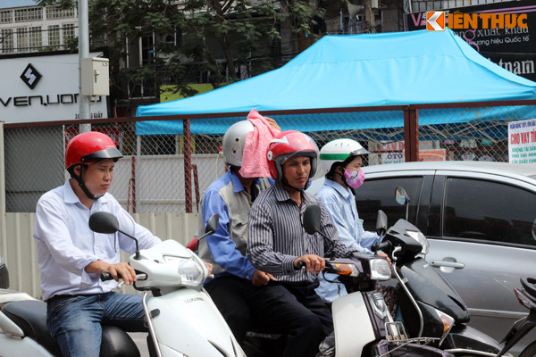 Hình ảnh ghi lại một người dân dùng khăn phủ lên phía trước chiếc mũ bảo hiểm đang đội trên đầu để giảm bớt đi không khí nóng nực. Ảnh chụp trên đường Cầu Giấy.
