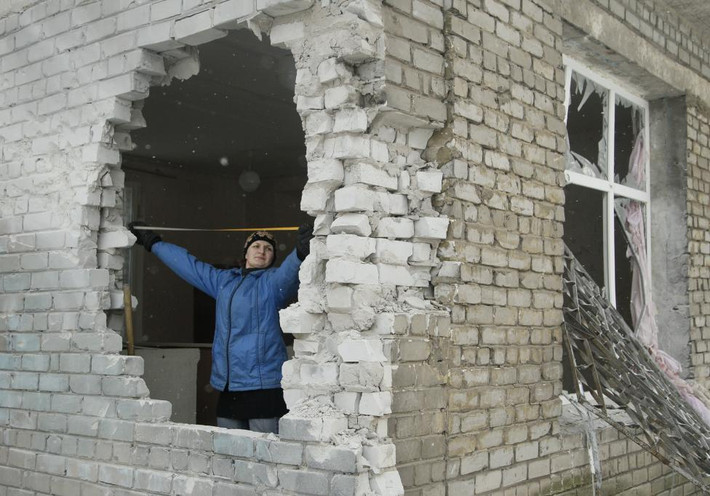 Người phụ nữ kiểm tra ngôi nhà bị hư hại do trúng pháo ở Donetsk hôm 3/2.