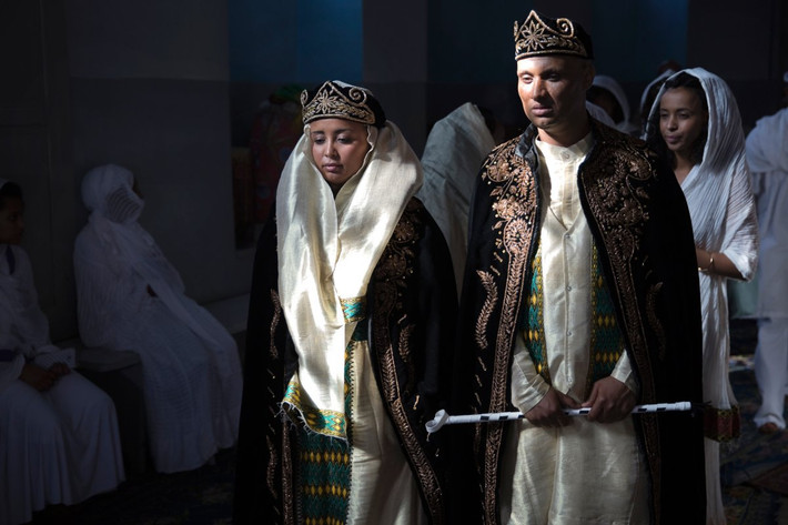 Trong đám cưới truyền thống của người Eritrea, cô dâu và chú rể sẽ đội mũ tối màu và khoác áo choàng màu tím và vàng.