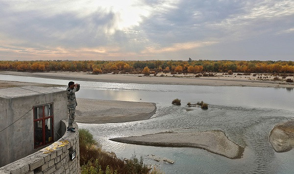 Một cảnh sát Afghanistan đứng quan sát bên bờ sông Helmand ở Lashkar Gah.