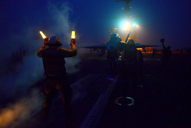 Các nhân viên kỹ thuật đang hướng dẫn tiêm kích F/A-18C vào vị trí phóng trên tàu sân bay USS John C. Stennis để chuẩn bị cất cánh. Hàng không mẫu hạm lớp Nimitz được thiết kế để hoạt động bất kể ngày đêm.