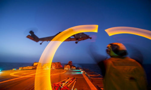 Một nhân viên kiểm soát không lưu đang hướng dẫn cho trực thăng MH-60S Sea Hawk hạ cánh trên boong tuần dương hạm USS Philippine Sea (lớp Ticonderoga). Nhiệm vụ của Sea Hawk là tiếp tế hàng hóa, trinh sát, chống ngầm, tìm kiếm cứu nạn, hay chuyên chở lực lượng đặc nhiệm. Đây là một khoảnh khắc hoạt động về đêm ấn tượng của Hải quân Mỹ.