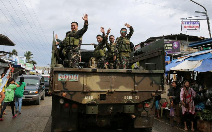Các binh sĩ Philippines vẫy tay chào người dân địa phương trên đường phố Marawi. Ảnh: Reuters.