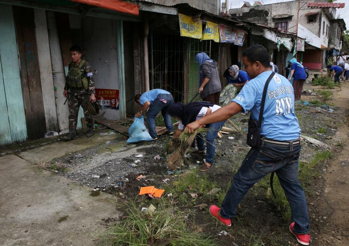 Người dân dọn dẹp đống đổ nát tại một khu vực trong thành phố Marawi. Ảnh: Reuters.