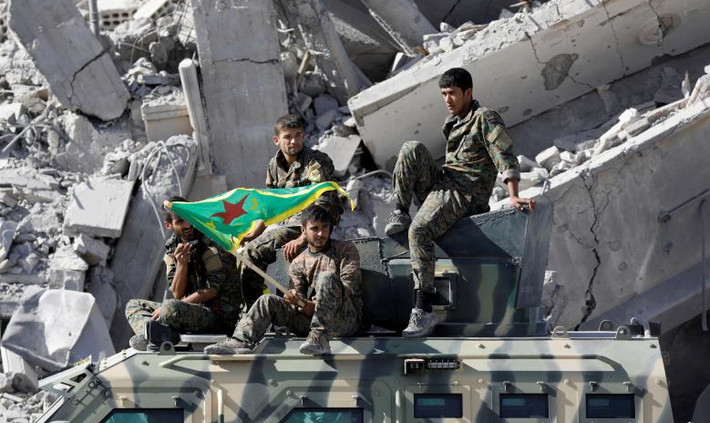 Các chiến binh SDF ngồi trên một chiếc xe quân sự ở thành phố Raqqa. Ảnh: Reuters.