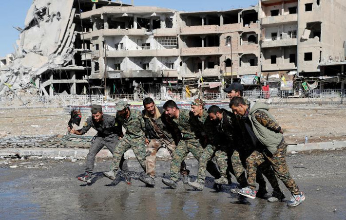 Các chiến binh SDF nhảy múa ăn mừng trên một con phố ở Raqqa. Ảnh: Reuters.