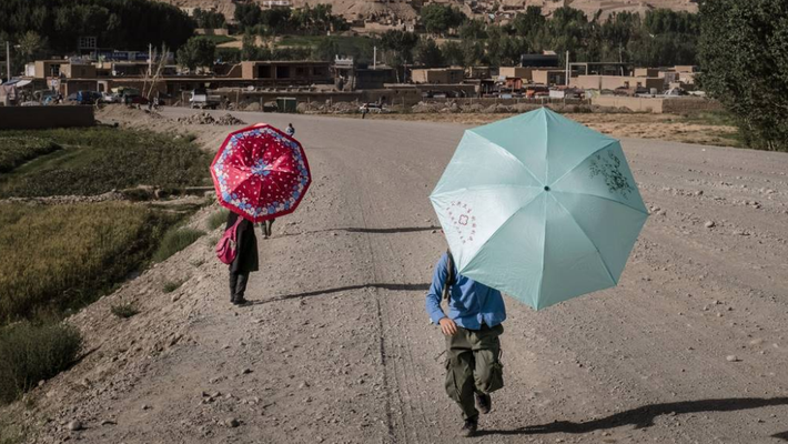 Các em nhỏ Afghanistan che ô khi đi dưới trời nắng nóng ở Bamiyan ngày 7/8. Ảnh: Getty Images.