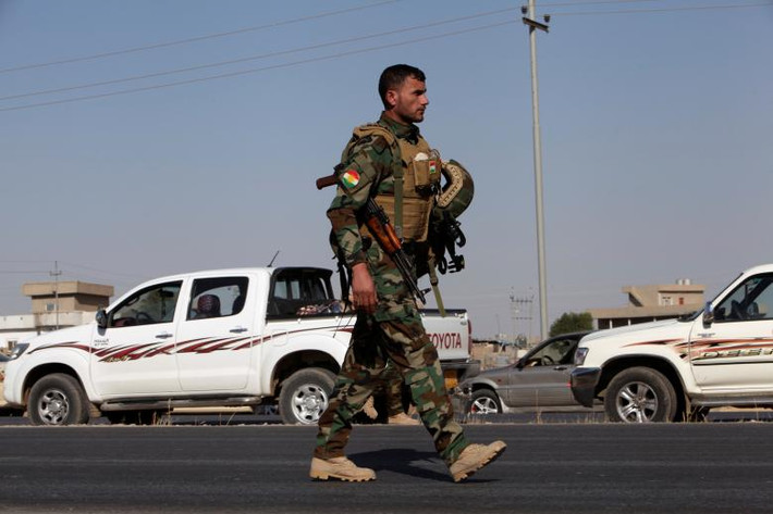 Một tay súng người Kurd đi bộ trên con đường gần thị trấn Altun Kupri. Ảnh: Reuters.