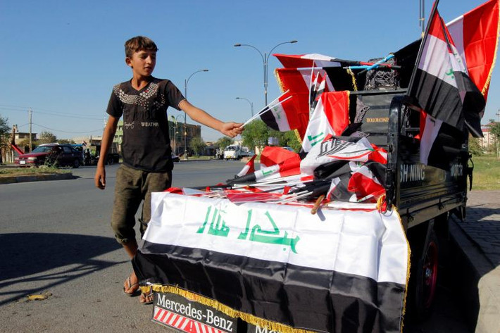 Bé trai bán lá cờ Iraq trên một con phố ở tỉnh Kirkuk. Ảnh: Reuters.