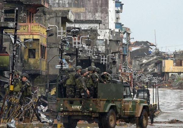 Xe quân sự chở các binh sĩ Philippines đi qua những tòa nhà bị hư hại trong các cuộc giao tranh tại Marawi. Ảnh: FNA.