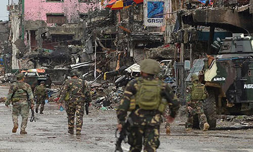 Các binh sĩ Philippines đi qua những tòa nhà đổ nát ở thành phố Marawi, miền nam nước này. Ảnh: FNA.