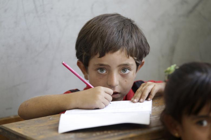 Một bé trai ngồi học ở tỉnh Idlib của đất nước Syria tháng 9/2015. Ảnh: Reuters.