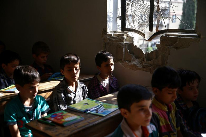 Các em học sinh ngồi học trong ngày đầu tiên ngôi trường mở cửa ở Douma, Syria, tháng 9/2017. Ảnh: Reuters.