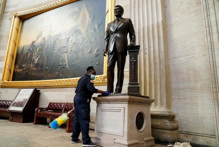 Một nhân viên lau bức tượng cựu Tổng thống Mỹ Ronald Reagan trong phòng Rotunda của tòa nhà Quốc hội sau đêm bạo loạn.