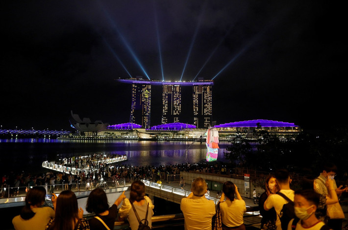 Người dân Singapore theo dõi màn trình diễn ánh sáng tại Vịnh Marina đêm giao thừa. Singapore đã hủy bỏ bắn pháo hoa do đại dịch COVID-19. Ảnh: Reuters.