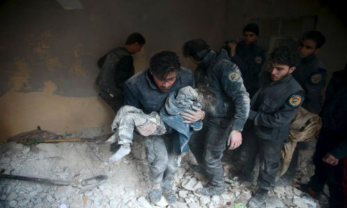 Người đàn ông bế một em nhỏ còn sống ra khỏi đống đổ nát tại thị trấn Douma, Ghouta ngày 10/1.