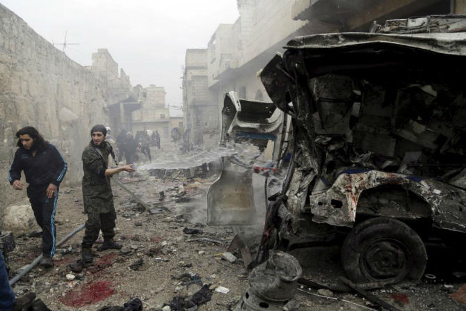 Người đàn ông "chữa cháy" cho chiếc xe cứu thương tại thị trấn Maaret al-Numan, tỉnh Idlib ngày 12/1.
