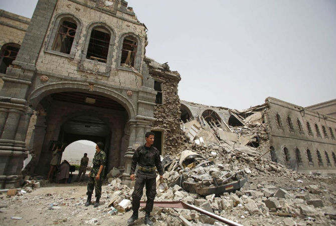 Các chiến binh Houthi đứng gác trước tòa nhà của Bộ Quốc phòng Yemen sau khi nó bị phá hủy bởi các cuộc không kích của liên quân Ả-rập ngày 10/6/2015.
