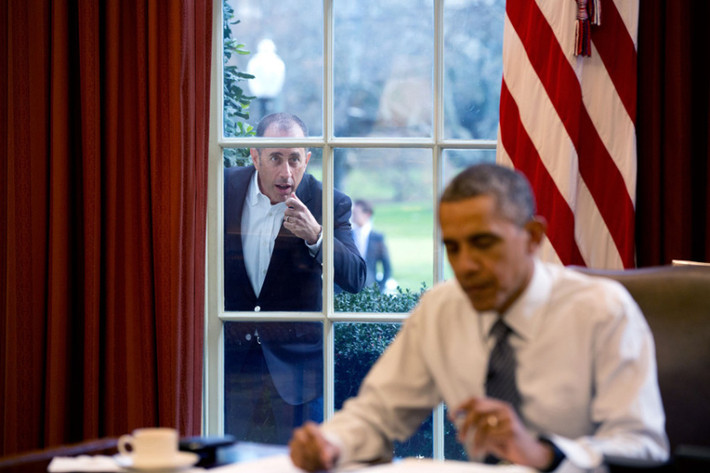 Ngày 7/12/2015: Diễn viên hài Jerry Seinfeld gõ cửa sổ của phòng Bầu dục nơi Tổng thống Obama đang ngồi để bắt đầu một cảnh quay trong loạt phim của anh.