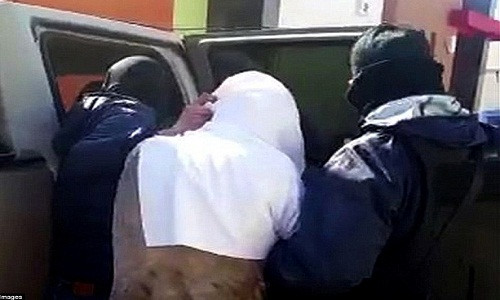 El Chapo – người trùm chiếc khăn trắng lên đầu – bị áp giải lên một chiếc SUV để tới một sân bay.