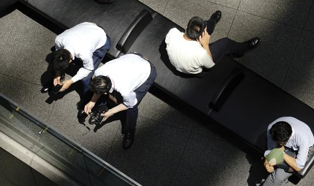 Mọi người ngồi nghỉ dưới một tòa nhà ở thủ đô Tokyo. Ảnh: AP.