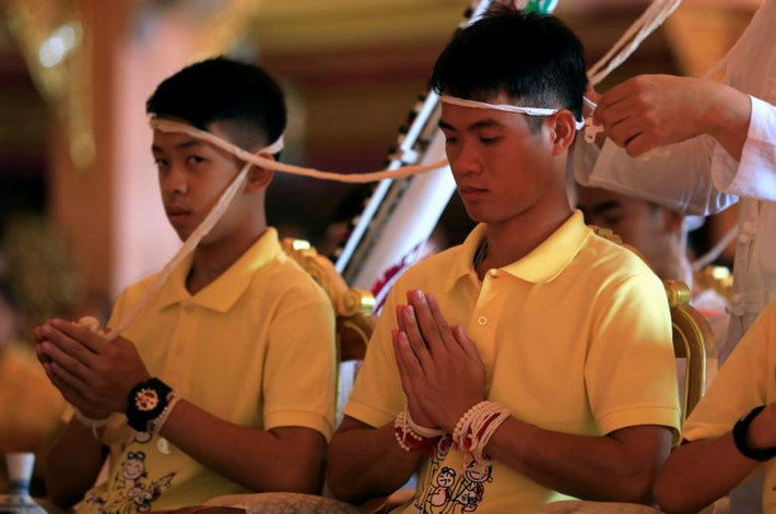 Mặc dù kết quả kiểm tra y tế lâm sàng cho thấy sức khỏe của toàn bộ đội bóng đã ổn định, song các bác sĩ vẫn lo ngại về nguy cơ sang chấn tâm lý xảy ra do các em còn nhỏ tuổi. Ảnh: Các cầu thủ của đội bóng nhí tham gia một nghi lễ tại ngôi chùa ở Mae Sai sau khi xuất viện.