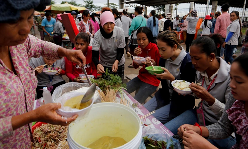 Một số công nhân ngồi ăn sáng tại khu chợ bên ngoài nhà máy trước khi vào làm việc.