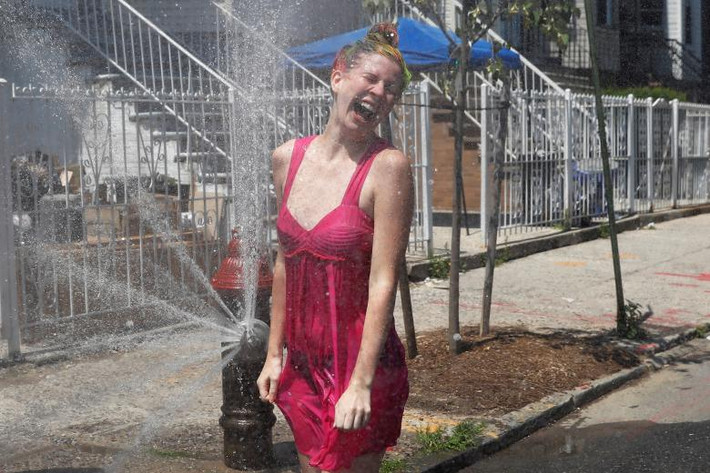 Cô gái “hạ hỏa” bằng cách đứng trước vòi phun nước mở ở Brooklyn.