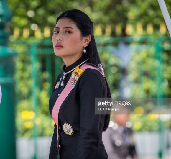 Được biết người phụ nữ quyền lực tên là Sirivannavari Nariratana, công chúa của Hoàng gia Thái Lan, cháu gái Quốc vương Bhumibol Adulyadej. Theo phong tục của người Thái, khi chụp hình chung với công chúa, người dân buộc phải quỳ.