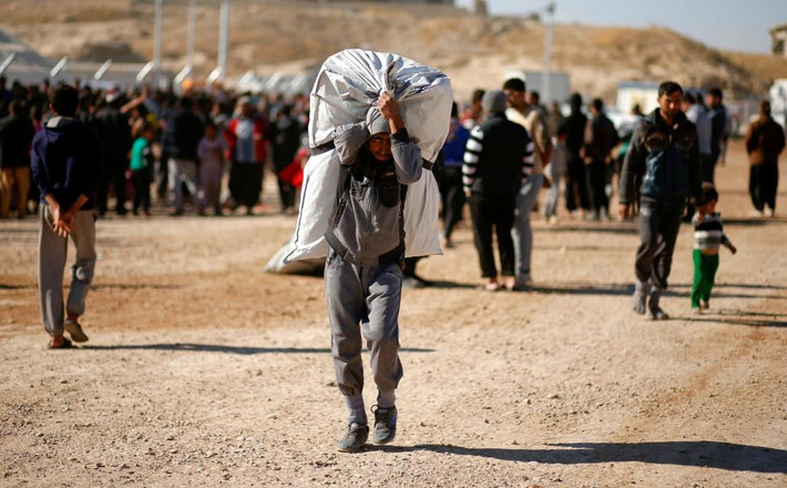 Một người đàn ông Iraq vác túi đồ cứu trợ ra khỏi khu trại Khazer ngày 21/11. Được biết, cho đến nay, 54 nghìn người dân đã phải sơ tán trong chiến dịch giải phóng Mosul.
