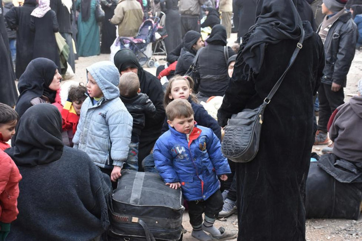 Người dân Syria chờ lên xe buýt tại một khu vực do chính phủ kiểm soát ở Aleppo hôm 29/11.
