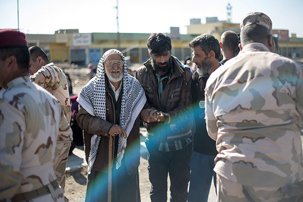 Binh sĩ quân đội Iraq đỡ một cụ già qua chốt kiểm soát trên một con đường ở phía đông Mosul.
