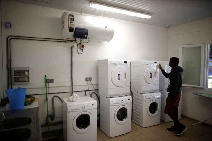 Một di dân đang sử dụng máy giặt để giặt đồ. (Nguồn ảnh: Reuters).