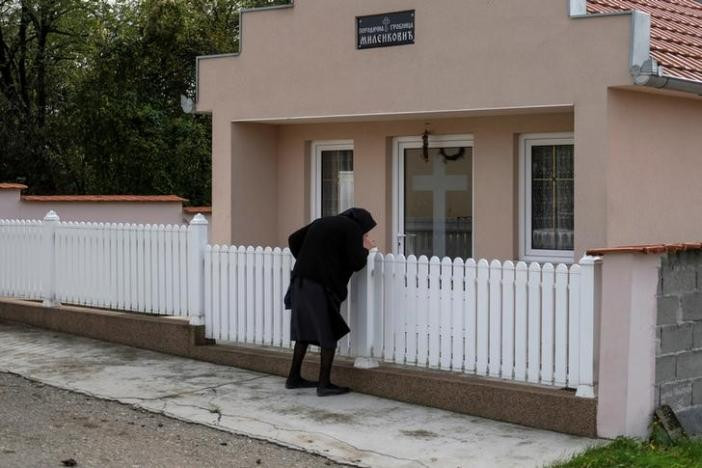 Một phụ nữ hôn lên hàng rào trước ngôi mộ lớn trong nghĩa trang ở làng Sapine, Serbia, ngày 25/10. (Nguồn ảnh: Reuters).