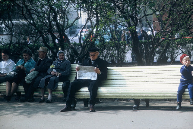 Một người đàn ông ngồi trên ghế đọc báo.