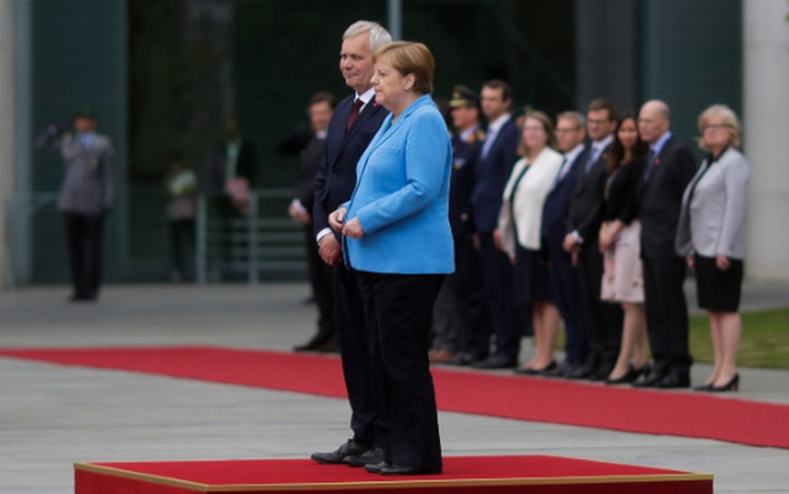 Bà Merkel đã phải đổi tư thế từ buông thõng tay sang nắm hai tay lại với nhau nhưng vẫn không khống chế được cơn run rẩy. Chỉ khi bà bước đi, tình trạng run rẩy mới biến mất. Ảnh: Time.