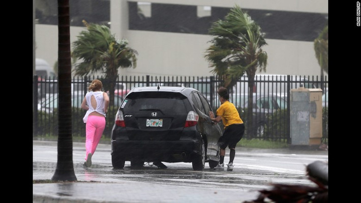 Người phụ nữ chạy vội lên chiếc ô tô ở Hialeah, Florida, khi siêu bão đổ bộ hôm 10/9. Ảnh: CNN.