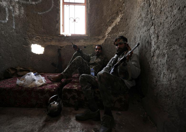 Hai chiến binh SDF cầm vũ khí khi ngồi trong một căn cứ ở Raqqa. Ảnh: Reuters.