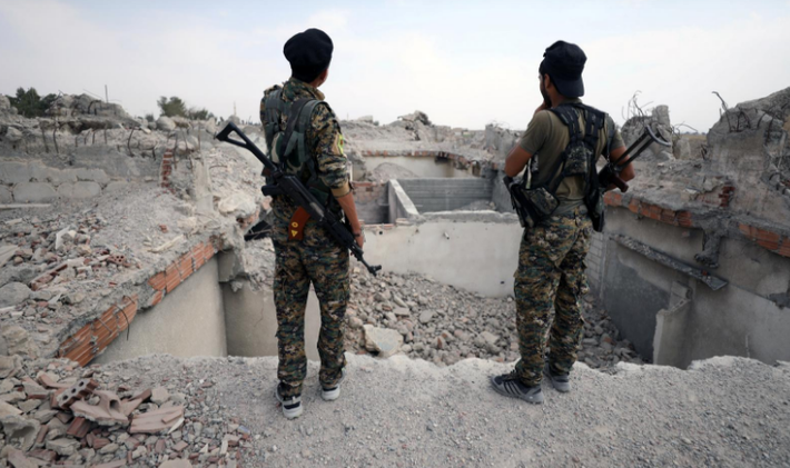 Chiến binh SDF đứng gần ngôi đền Uwais al-Qarni bị phá hủy ở Raqqa ngày 16/9. Ảnh: Reuters.