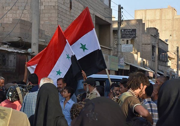 Người dân cầm lá cờ Syria trên một con phố đông đúc. Ảnh: FNA.