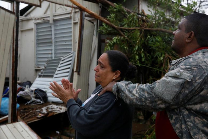 Người phụ nữ buồn rầu nhìn ngôi nhà của mẹ cô bị tàn phá ở Guayama. Ảnh: Reuters.