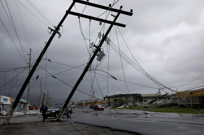 Những cây cột điện sắp đổ xuống đường ở Guayama. Ảnh: Reuters.