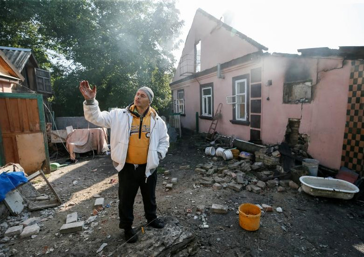 Người đàn ông đứng trước ngôi nhà bị hư hại. Ảnh: Reuters.