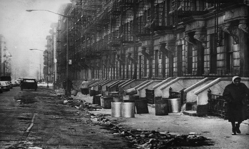 Người phụ nữ đi qua một khu ổ chuột ở Harlem năm 1965. Ảnh: ATI.