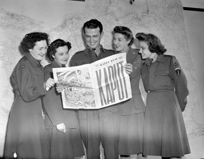 Một nhóm người đọc thông tin về ngày chiến thắng trên báo Maple Leaf ở thủ đô Paris ngày 11/5/1945. Ảnh: ATI.