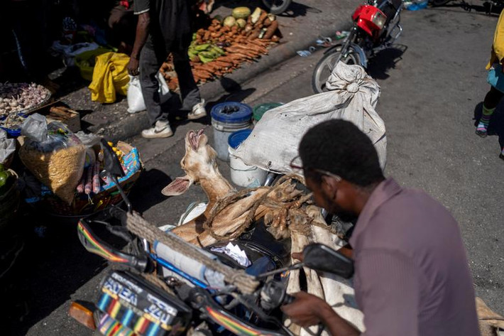 Người đàn ông mang chú dê đi bán tại một khu chợ ở Port-au-Prince, ngày 17/7.