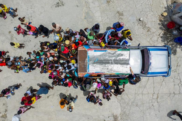 Theo Reuters, bạo lực gia tăng ở thủ đô Port-au-Prince của Haiti khiến hàng nghìn người phải sơ tán và làm trầm trọng thêm cuộc khủng hoảng nhân đạo ở nước này. Nhiều người dân Haiti phải sống tạm bợ trong những nơi trú ẩn tạm thời. Ảnh: Rất đông người tập trung xung quanh một chiếc ô tô, nơi các tình nguyện viên phân phát đồ ăn cho người tị nạn tại nhà thờ Saint Yves, thủ đô Haiti, ngày 26/7. (Nguồn ảnh: Reuters)