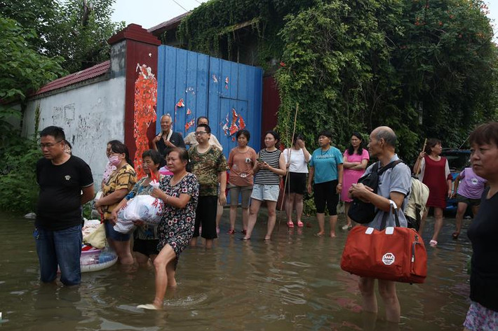 Nhiều người dân ở ngôi làng Beiguan mang theo đồ đạc, chờ được đưa ra khỏi khu vực ngập lụt.