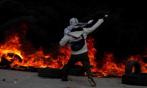 Một người biểu tình Palestine ném đá về phía lực lượng an ninh Israel gần thành phố Ramallah ở Bờ Tây. Ảnh: Reuters.